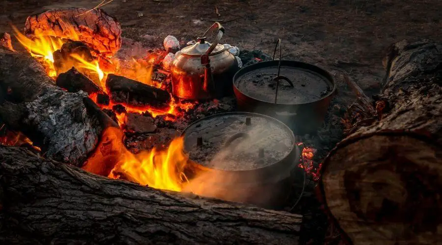 Cooking food with pots and pans over an open fire 