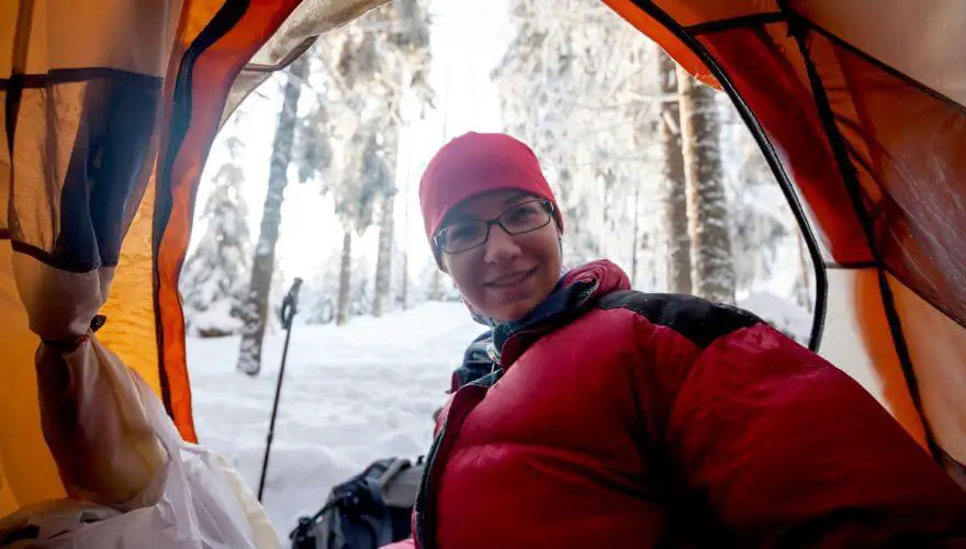 Vrouw zit in haar tent op een winterkampeertrip